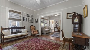 Ein geräumiges Wohnzimmer mit einer hölzernen Bank, einem Sofa, einem Sessel und einem Schreibtisch mit einer Uhr.
