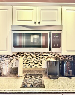 A kitchen with a stainless steel microwave, a coffee maker, and a toaster.
