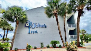 The exterior of St. John's Inn with a brick facade, palm trees, and a clear sky. - NEW! 2nd Floor Studio w/Kitchen (Myrtle Beach)