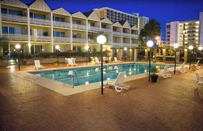 Ein Hotelpoolbereich mit mehreren Balkonebenen, Liegestühlen und einem Schwimmbecken.