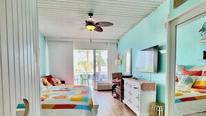 A room with two beds, a ceiling fan, a TV, and a view of the outdoors. - NEW! 2nd Floor Studio w/Kitchen (Myrtle Beach)