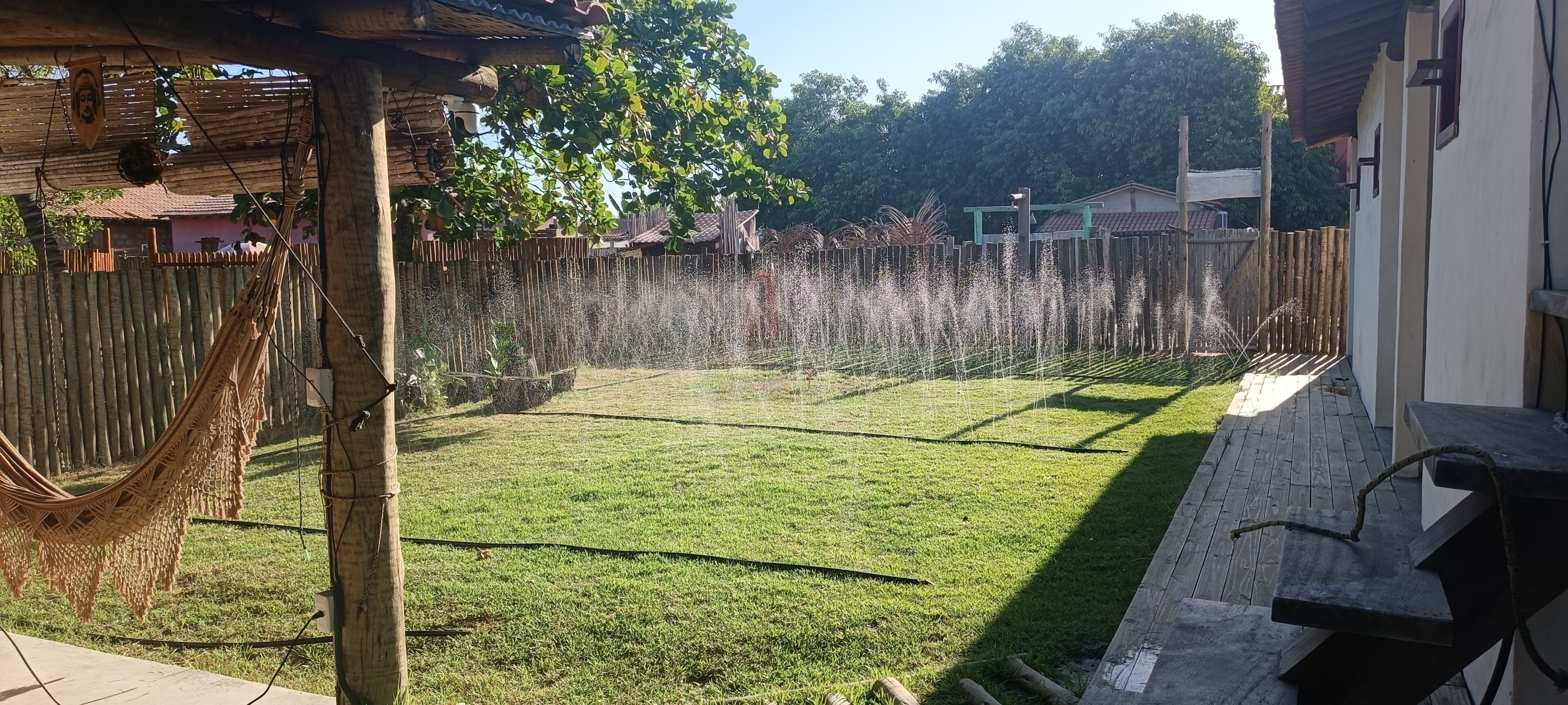 A backyard with a hammock, a wooden fence, and a grassy lawn.