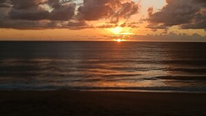 A sunset over a beach with clouds in the sky. - Vila Santa Fé Caraíva  (Porto Seguro)