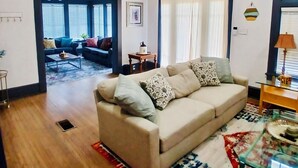 A living room with a beige sofa, a glass coffee table, and a patterned rug.