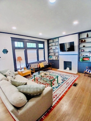 A living room with a sofa, a coffee table, a TV mounted on the wall, and a fireplace.