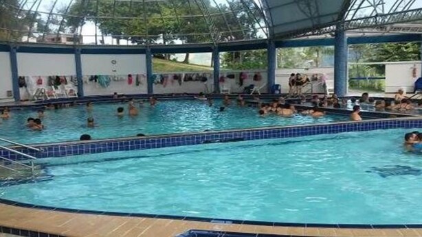 An indoor swimming pool with multiple lanes, a covered area, and a tiled deck surrounding the pool. - Studio climatizado wifi no centro (Piratuba)