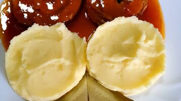 A plate with two meat rolls, mashed potatoes, and pickles.