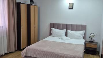 A neatly arranged bedroom with a bed, a bedside table, a wardrobe, and a patterned rug.