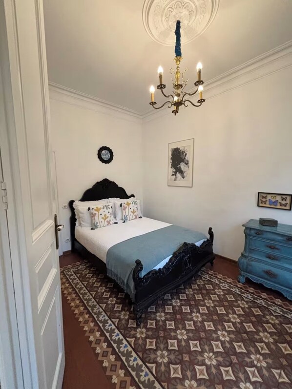A bedroom with a bed, a dresser, a chandelier, and a patterned rug. - Central and spacious modernist apartment in the heart of Barcelona !!!!! (Barcelona)