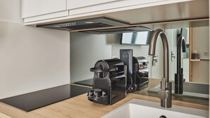 A modern kitchen with a sleek black coffee machine, a stainless steel faucet, and a minimalist design. - Superb Studio Tour Eiffel/champ de Mars (Paris)