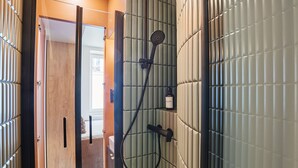 A bathroom with a shower, a wooden door, and a tiled wall. - Superb Studio Tour Eiffel/champ de Mars (Paris)