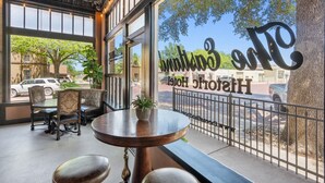 Un rincón acogedor con una mesa y sillas, ventanas amplias con vista a la calle y un letrero que dice "The Historic Hotel".