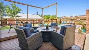 Un patio exterior con mobiliario de mimbre, una mesa redonda y una zona de piscina.