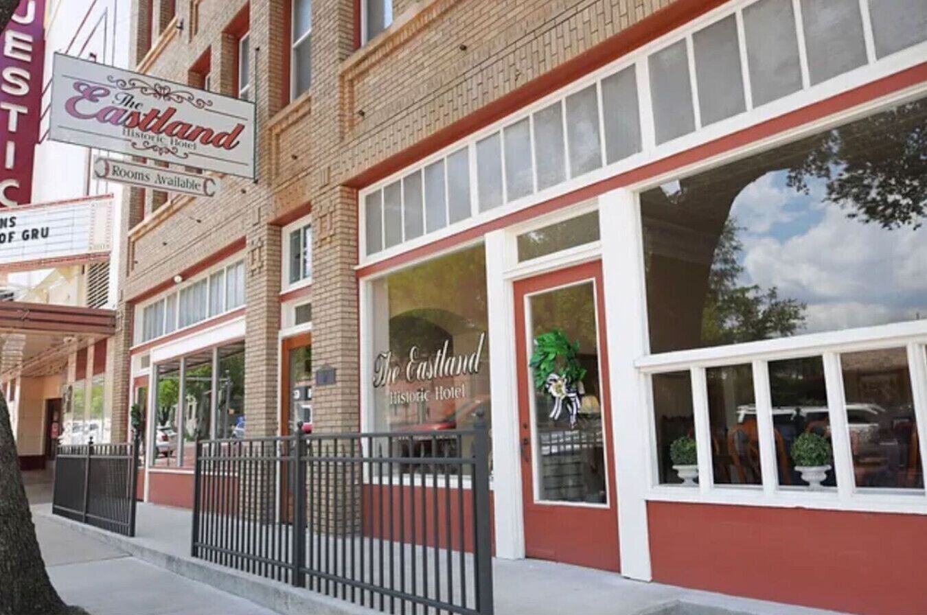 A historic hotel with a red and white facade, large windows, and a sign indicating rooms are available.
