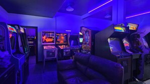 A room with arcade machines, a leather chair, and a ceiling fan.