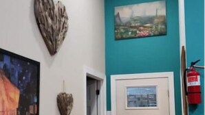 A hallway with a teal accent wall, a white door, and a painting above it.