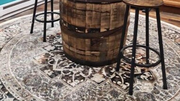 A kitchen with teal walls, wooden cabinets, a stainless steel refrigerator, and a wooden barrel stool with a basket on top.
