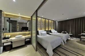 Een moderne hotelkamer met een grote spiegel, twee bedden, een wastafel en een kleine tafel.