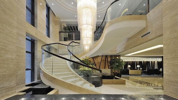 A modern hotel lobby with a curved staircase, a large chandelier, and a seating area with a coffee table and chairs. - Yangzhou Convention Center(Mingyue Lake Store) (Yangzhou)