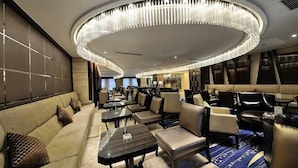 A modern hotel lobby with a circular chandelier, leather sofas, and dining tables. - Yangzhou Convention Center(Mingyue Lake Store) (Yangzhou)