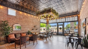 Un espacio interior amplio con paredes de ladrillo, muebles de madera y plantas colgantes.