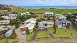 Un barrio residencial con casas, una carretera y vista al mar.