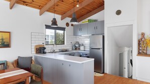 Una cocina moderna con una isla central, electrodomésticos de acero inoxidable y techo de madera.