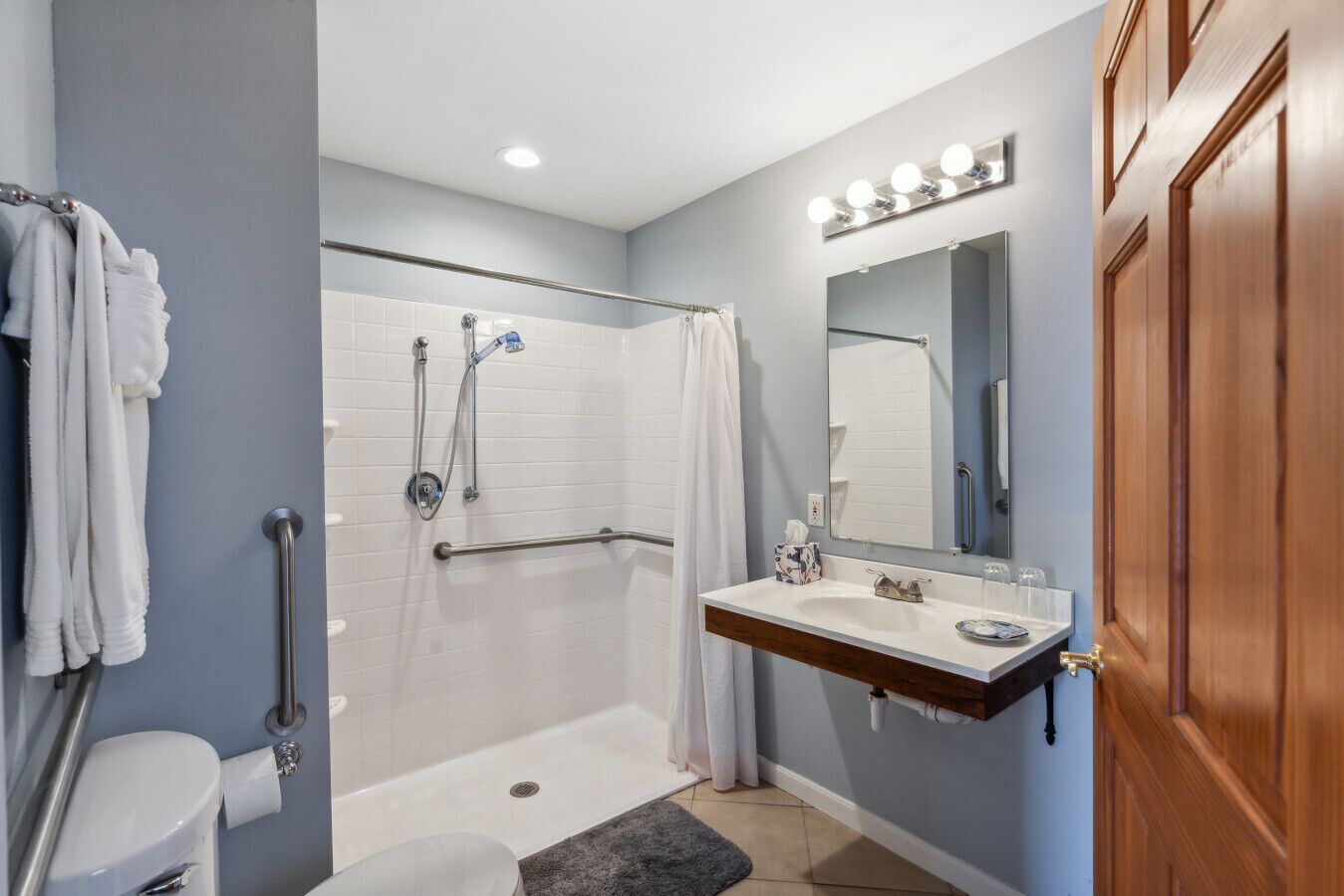 A bathroom with a walk-in shower, a vanity with a mirror, and a toilet.