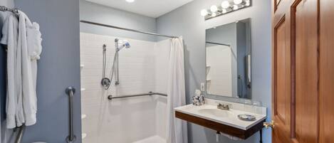 A bathroom with a walk-in shower, a vanity with a mirror, and a toilet.