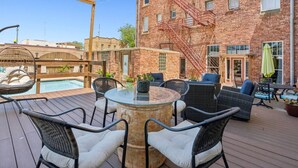 A rooftop patio with outdoor seating, a pool, and a brick building with a fire escape.