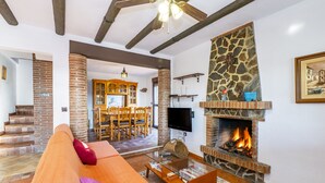 Amplia sala de estar con chimenea, un sofá y un comedor con mesa y sillas de madera.