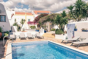 Una piscina al aire libre, sillones reclinables de piscina