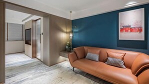 A modern living room with a leather sofa, a blue accent wall, and a framed artwork. - Beijing Fuyou Street Hotel (Xidan Branch) (Beijing)