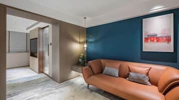A modern living room with a leather sofa, a blue accent wall, and a framed artwork.