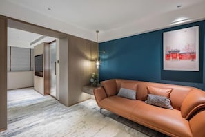 A modern living room with a leather sofa, a blue accent wall, and a framed artwork.
