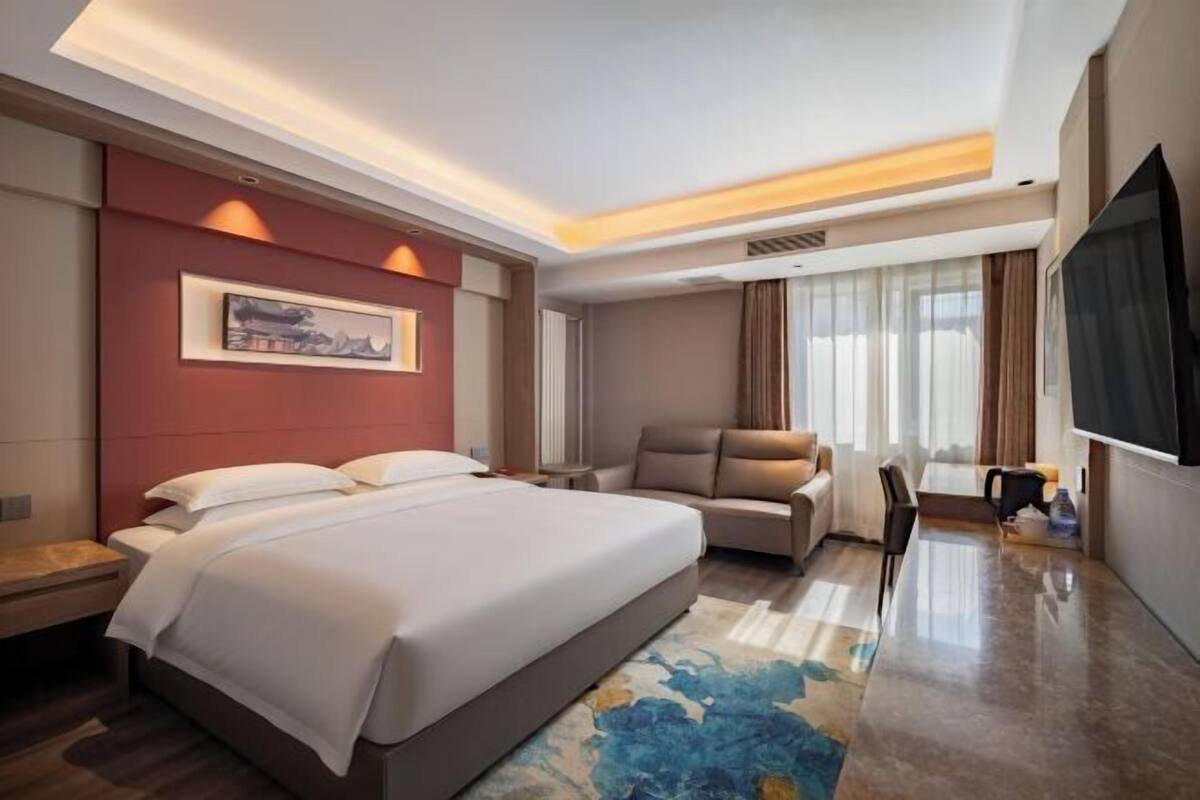 Een hotelkamer met een groot bed, een bank, een televisie en een bureau.