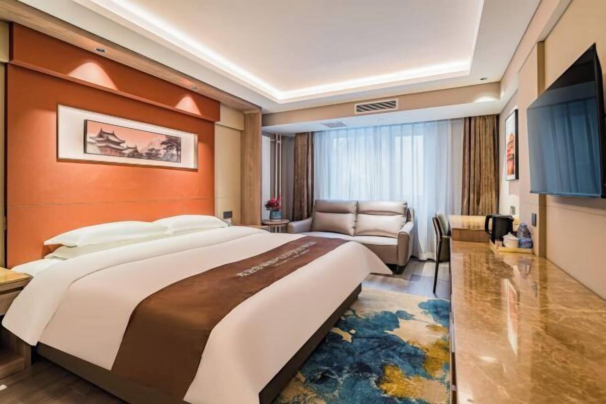 Een hotelkamer met een groot bed, een bank, een televisie en een schilderij aan de muur.