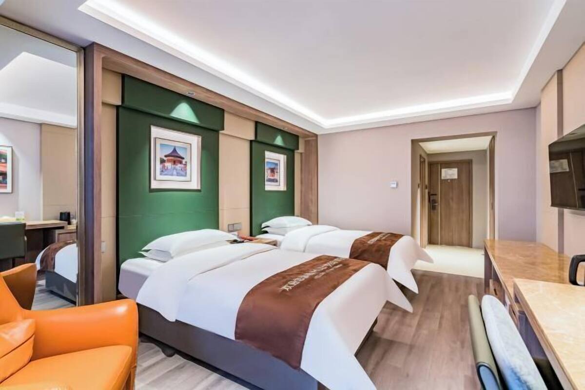 Een hotelkamer met twee bedden, een bureau, een stoel en een televisie.
