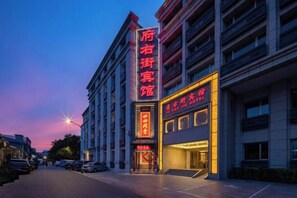 Un hotel con un cartel vertical llamativo, una entrada bien iluminada y una fachada de edificio moderna.