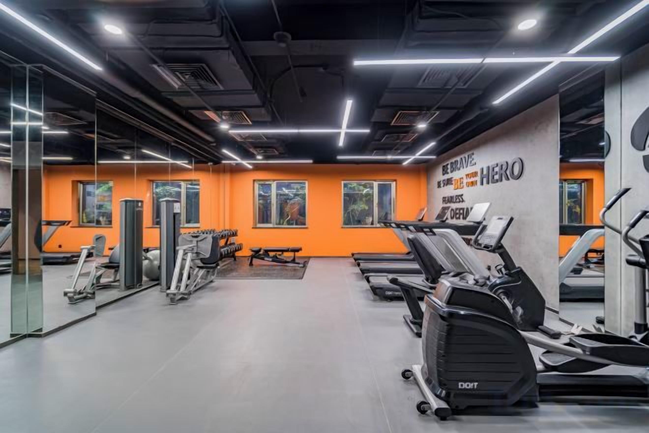 A gym with exercise equipment, mirrors, and motivational wall text.