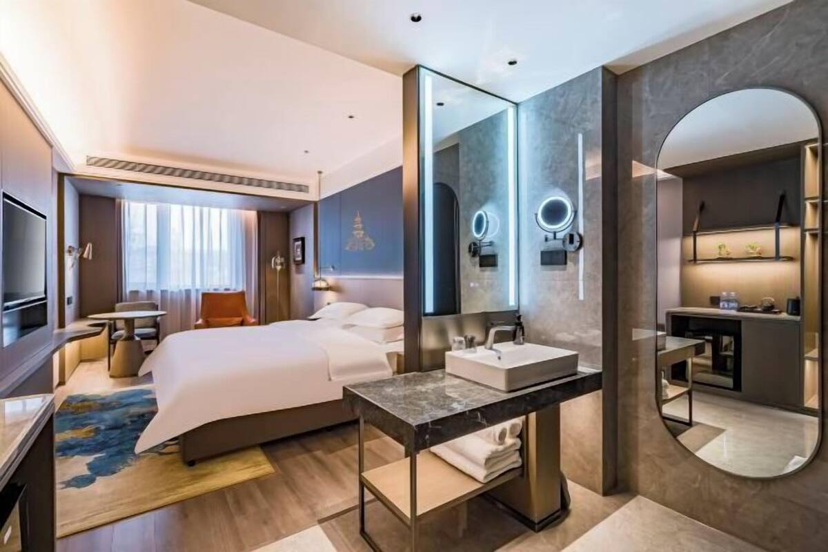 Een moderne hotelkamer met een groot bed, een badkamer met een wastafel en een grote spiegel.