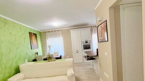 A living room with a sofa, a dining area with a table and chairs, and a kitchen with cabinets and appliances. - Casa Magenta Apartment 2 (Valeggio sul Mincio)