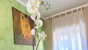 A room with a green wall, a painting, a desk, a chair, a laptop, and a welcome sign. - Casa Magenta Apartment 2 (Valeggio sul Mincio)