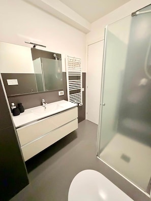 A modern bathroom with a white sink, mirror, and toilet.