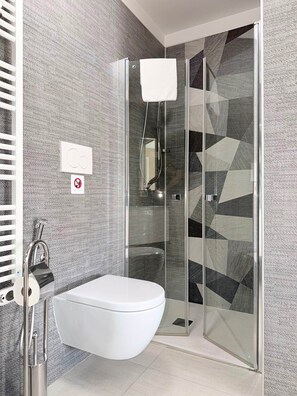 Ein modernes Badezimmer mit Duschkabine aus Glas, einer weißen Toilette und einem Handtuchhalter.