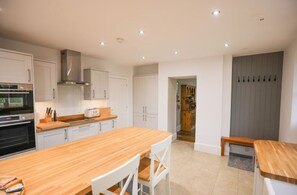 A modern kitchen with white cabinets, a wooden countertop, and a built-in oven. - The Old Farmhouse · Stunning farmhouse in Cambridgeshire countryside (Sawtry)