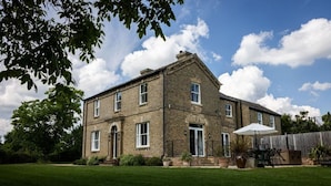A two-story brick house with a front door, windows, and a patio area with outdoor furniture.