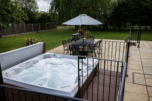 Un jacuzzi con una mesa y sillas, rodeado por una cerca, en un patio trasero.