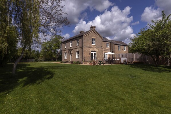 A large brick building with a well-maintained lawn and a patio area with outdoor furniture.