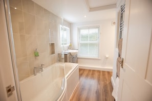 A modern bathroom with a bathtub, a sink, and a window with blinds. - The Maid's Cottage  · Rural hideaway in a cosy farm cottage with hot tub (Sawtry)